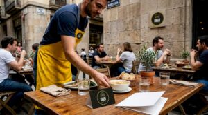 Un camarero atiende a los clientes en la terraza mientras les ofrece el menú del día.