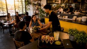 Ambiente de un restaurante de comida rápida con estilo moderno, donde un camarero atiende a varios clientes.