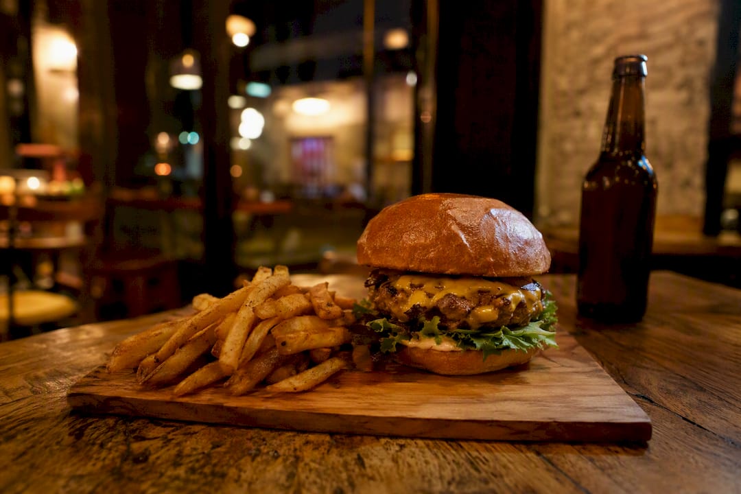 Hamburguesa y papas fritas en mesa de bar a altas horas