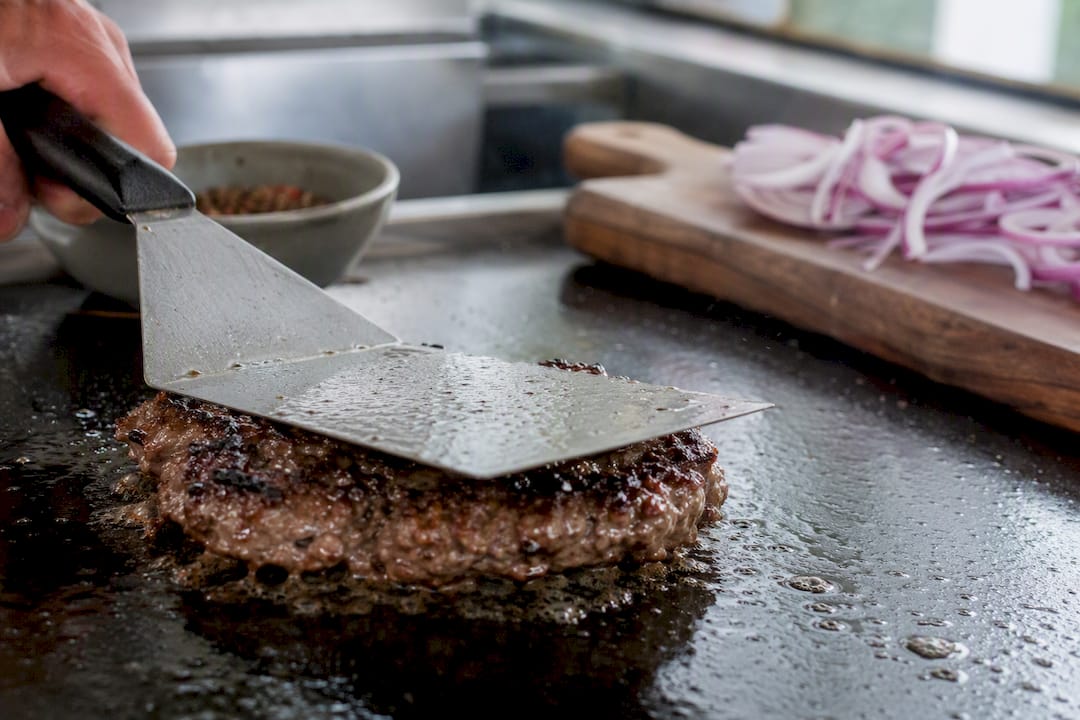 Hamburguesa smash fresca en la plancha caliente