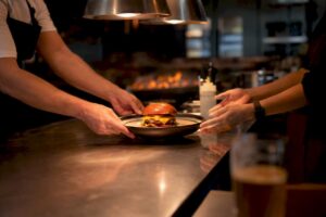 Un chef da los últimos toques a una hamburguesa gourmet en medio del ajetreo de la cocina.