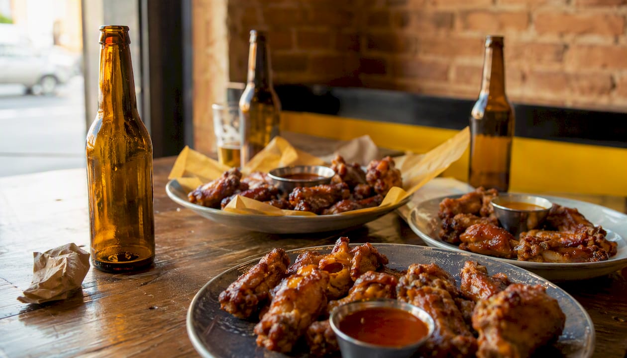 Distintos platos de alitas de pollo servidos sobre una mesa de madera
