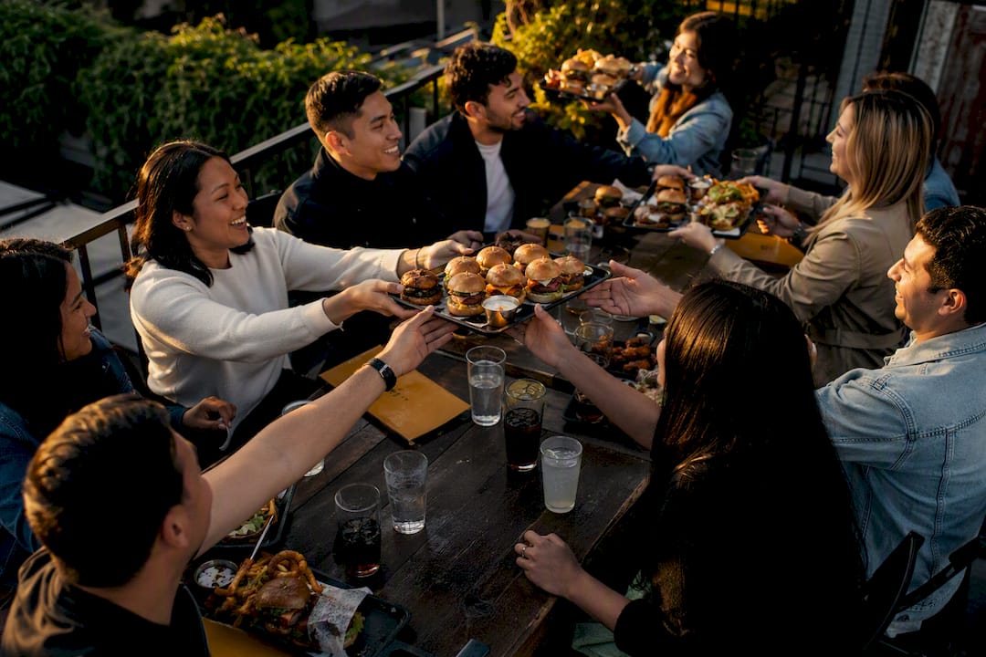 Manos pasando platos para compartir en una cena grupal