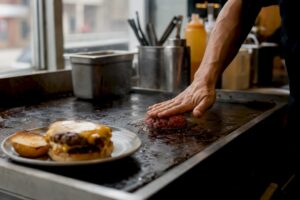 Chef aplastando la hamburguesa de carne en la plancha