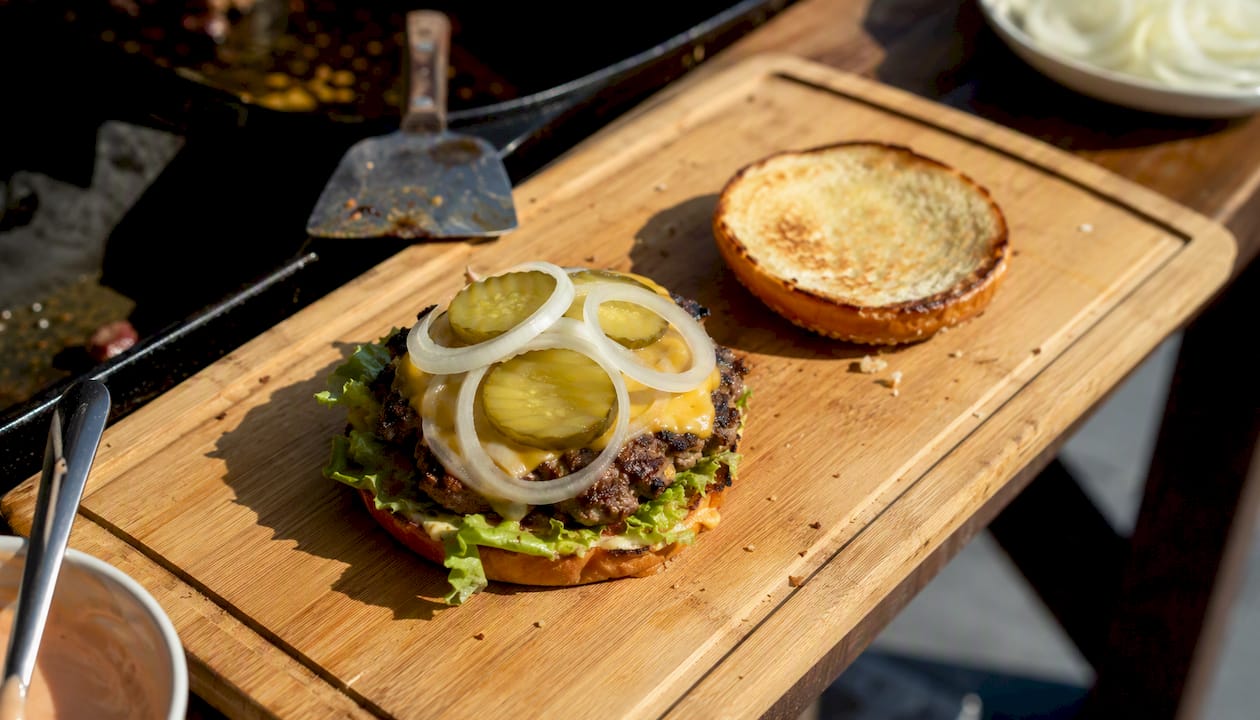 Montando las capas de una smash burger sobre una tabla de madera