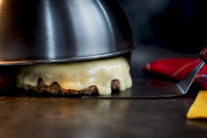 Queso derritiéndose sobre una hamburguesa en la plancha