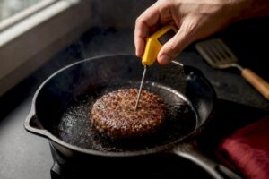 Termómetro tomando la temperatura en el centro de una hamburguesa
