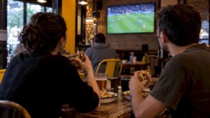 Los clientes cenan hamburguesas mientras ven un partido