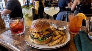 Hamburguesa artesanal acompañada de varios cócteles